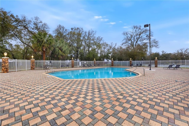 community pool with a patio area and fence