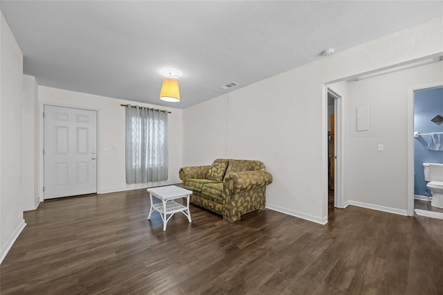 living area featuring visible vents, baseboards, and wood finished floors