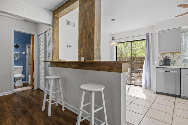 kitchen featuring visible vents, dishwasher, a breakfast bar area, and gray cabinetry