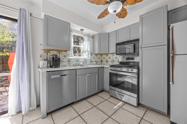 kitchen with a sink, gray cabinetry, light countertops, appliances with stainless steel finishes, and tasteful backsplash