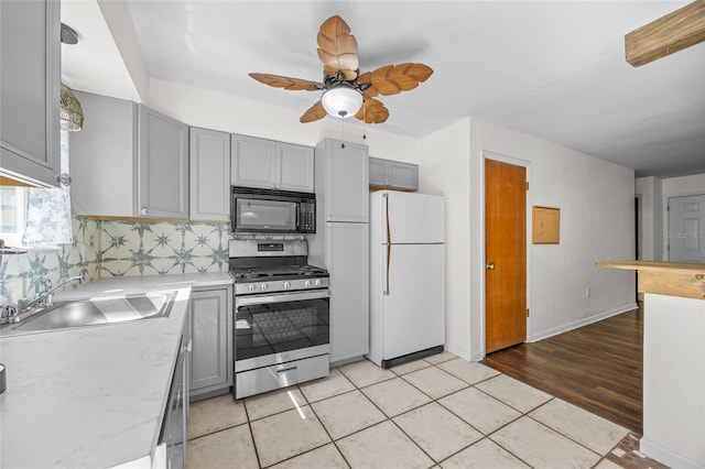 kitchen featuring gray cabinets, gas stove, freestanding refrigerator, and black microwave