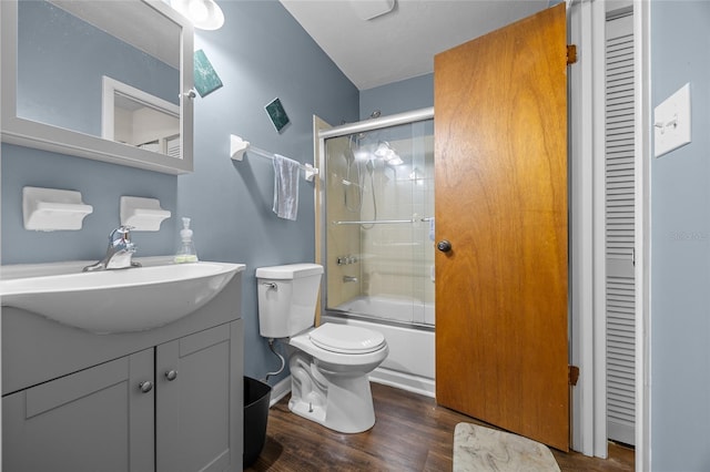 full bathroom with vanity, wood finished floors, enclosed tub / shower combo, a closet, and toilet