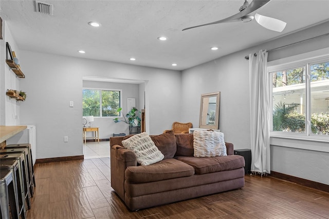 living area featuring a ceiling fan, wood finished floors, visible vents, baseboards, and recessed lighting