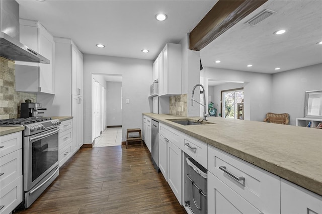 kitchen featuring dark wood-style floors, visible vents, a sink, appliances with stainless steel finishes, and wall chimney range hood