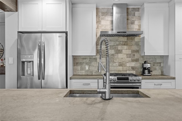 kitchen featuring backsplash, white cabinetry, stainless steel appliances, and wall chimney exhaust hood