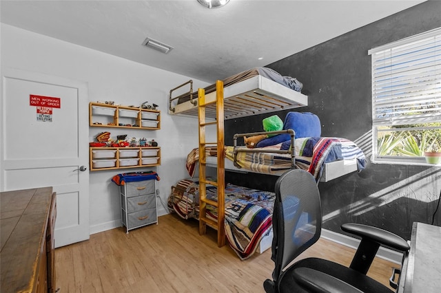 bedroom featuring visible vents, baseboards, and wood finished floors