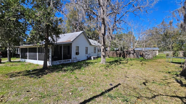 exterior space with fence, a sunroom, a trampoline, a lawn, and metal roof