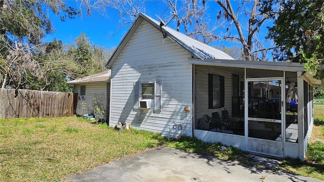 view of property exterior featuring a lawn, fence, and a sunroom