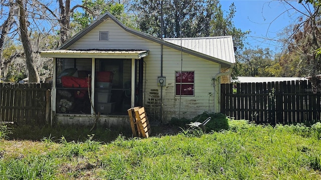 view of property exterior featuring fence, a sunroom, and metal roof