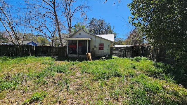 rear view of property with a fenced backyard and a sunroom