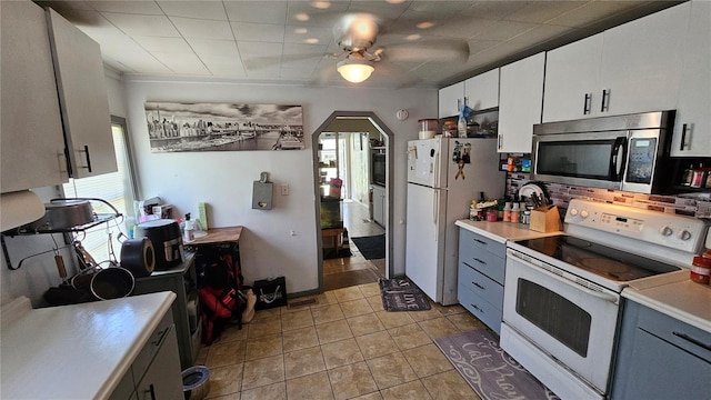 kitchen with arched walkways, white appliances, white cabinetry, and light countertops