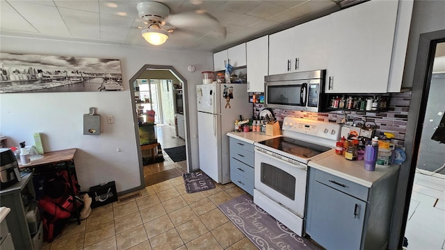 kitchen featuring white cabinetry, white appliances, light countertops, and arched walkways