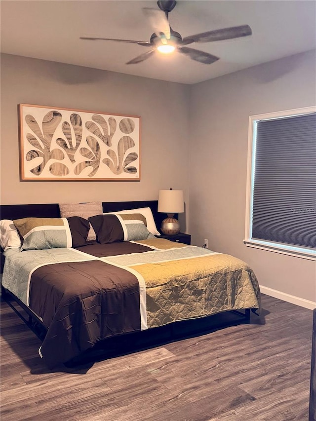 bedroom with a ceiling fan, wood finished floors, and baseboards