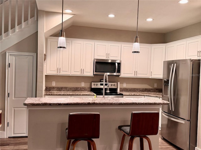 kitchen featuring a kitchen island, decorative light fixtures, a breakfast bar, white cabinets, and stainless steel appliances