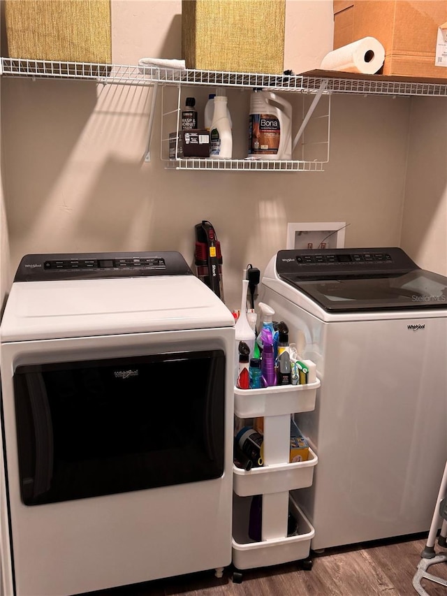 clothes washing area with washer and clothes dryer, laundry area, and wood finished floors