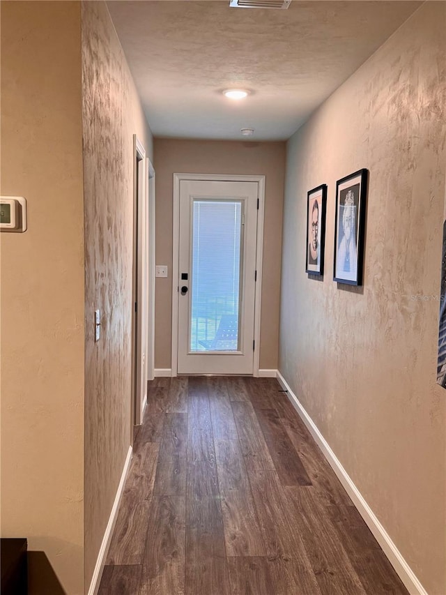 entryway with dark wood finished floors, visible vents, baseboards, and a textured wall