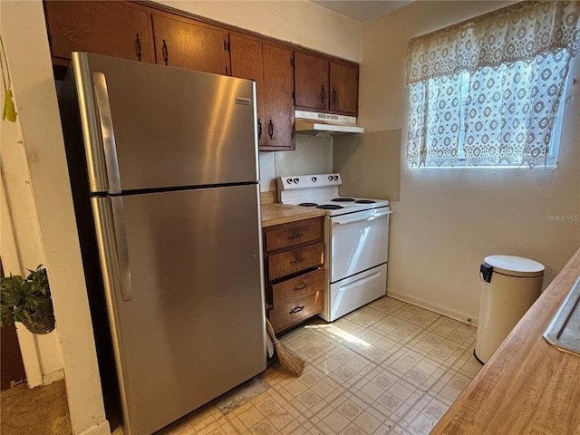 kitchen featuring baseboards, under cabinet range hood, light countertops, freestanding refrigerator, and white electric stove