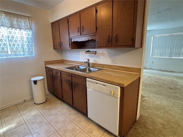 kitchen with baseboards, light floors, light colored carpet, white dishwasher, and a sink