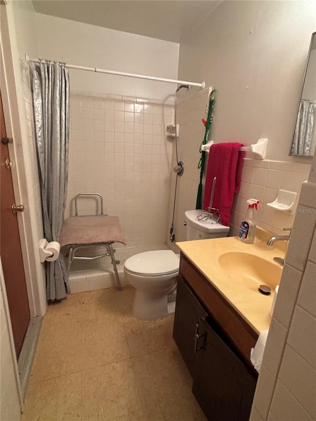 full bathroom featuring vanity, tile walls, toilet, and a tile shower