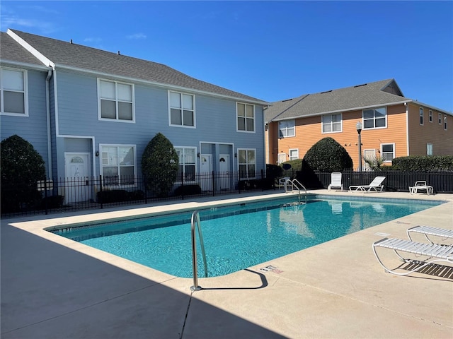 community pool with a patio area and fence