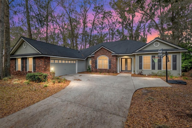 ranch-style house with a garage, brick siding, driveway, and french doors