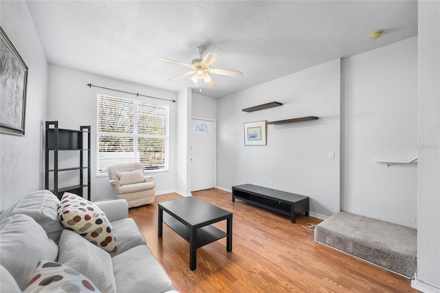 living room with ceiling fan, baseboards, and wood finished floors