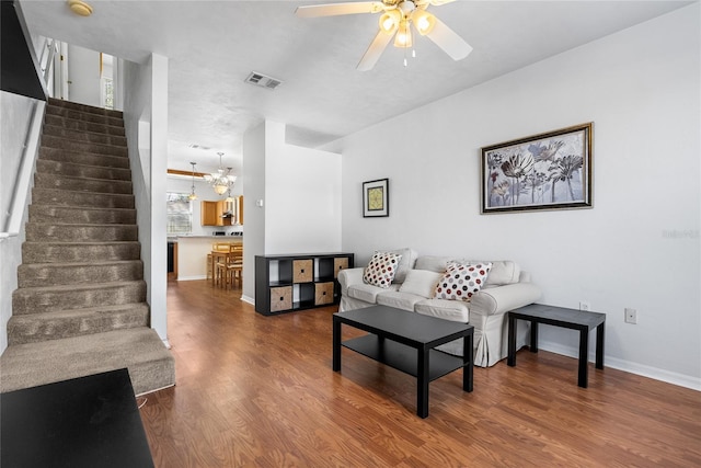 living area featuring visible vents, baseboards, stairway, ceiling fan with notable chandelier, and wood finished floors