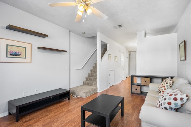 living room featuring visible vents, baseboards, stairs, wood finished floors, and a ceiling fan