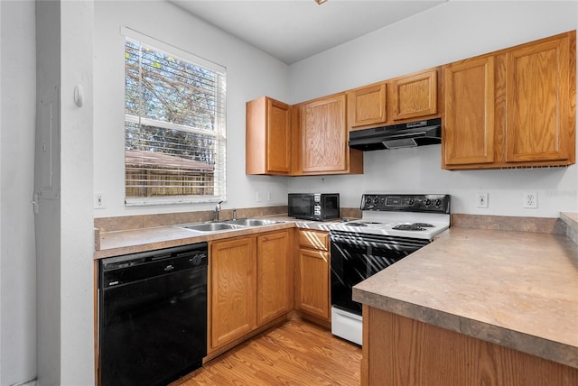 kitchen featuring a sink, black appliances, light countertops, light wood-style floors, and under cabinet range hood