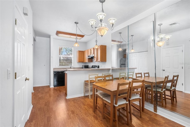 dining area featuring a notable chandelier, baseboards, visible vents, and wood finished floors