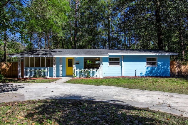 single story home featuring covered porch, a front yard, and fence