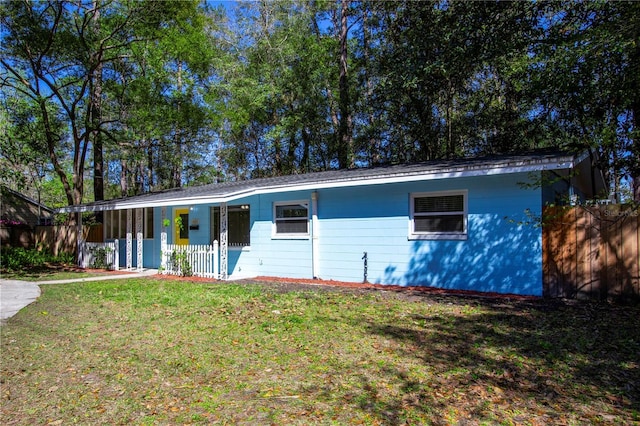 single story home with covered porch, a front yard, and fence