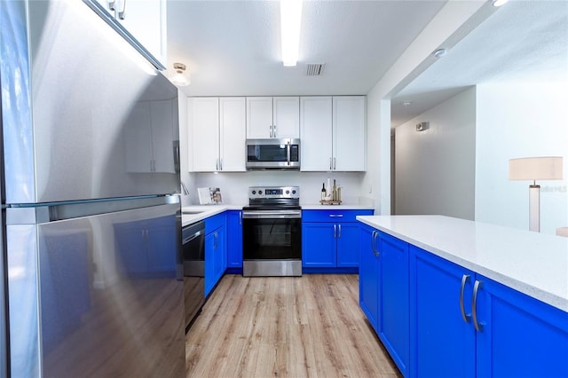 kitchen featuring white cabinets, appliances with stainless steel finishes, light countertops, and blue cabinets