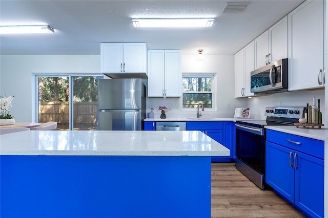 kitchen featuring blue cabinets, visible vents, a sink, light wood-style floors, and appliances with stainless steel finishes