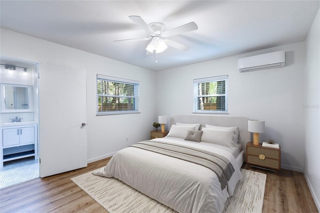 bedroom with ceiling fan, a wall mounted AC, baseboards, and wood finished floors