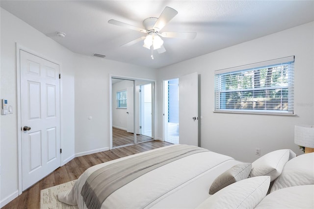 bedroom with a ceiling fan, wood finished floors, baseboards, and a closet