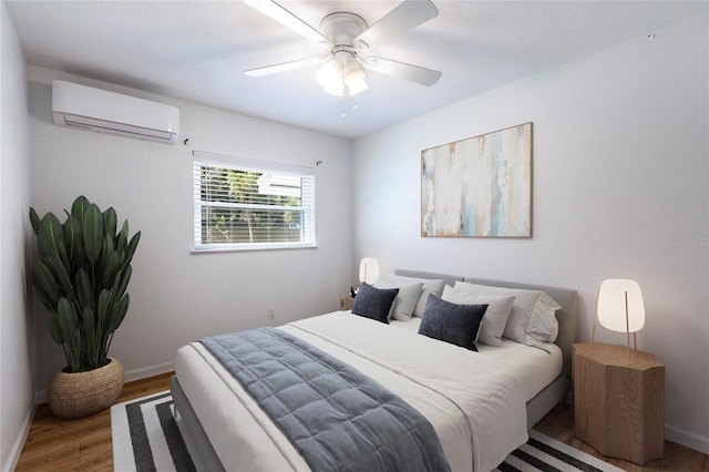 bedroom featuring a wall mounted air conditioner, baseboards, wood finished floors, and ceiling fan