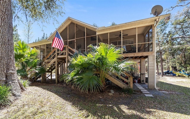 back of house with stairs, a ceiling fan, and a sunroom