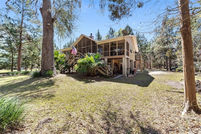 back of property featuring a yard, a ceiling fan, stairs, and a sunroom