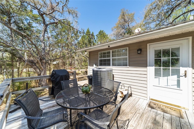 wooden deck with central AC unit, outdoor dining space, and a grill