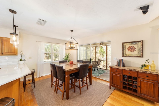 dining area featuring a notable chandelier, visible vents, light wood-type flooring, and baseboards