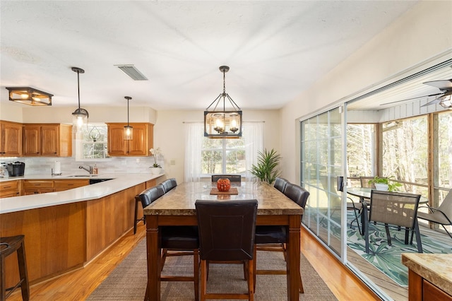 dining space featuring visible vents, light wood-style floors, and an inviting chandelier