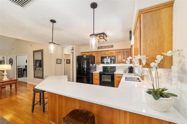 kitchen featuring visible vents, light countertops, a peninsula, black appliances, and a sink