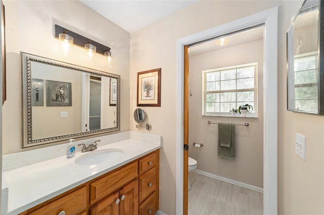 bathroom with toilet, vanity, and baseboards