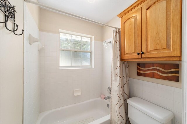 full bathroom featuring tile walls, toilet, and shower / bathtub combination with curtain