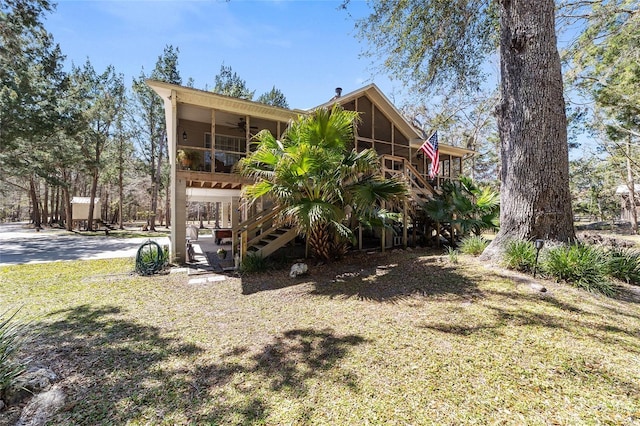 back of house featuring stairs, a ceiling fan, driveway, and a sunroom