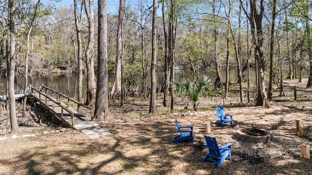 view of yard featuring a view of trees and an outdoor fire pit