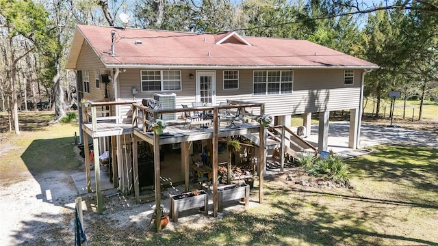 back of house with stairway, cooling unit, roof with shingles, a wooden deck, and gravel driveway