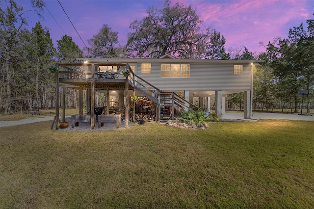 back of property at dusk featuring stairway, a yard, and a wooden deck