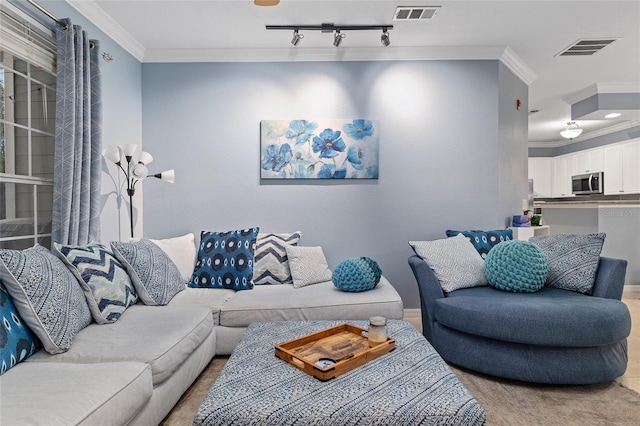 living area with crown molding, rail lighting, and visible vents